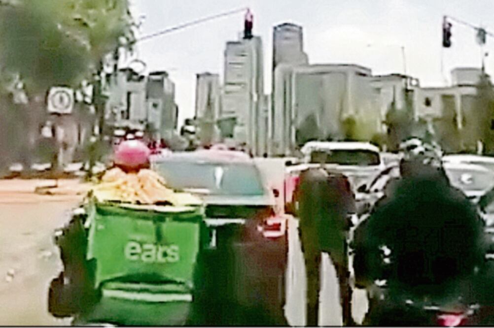 Momento en el que dos de los motociclistas extraen de la bolsa repartidora armas para asaltar a un automovilista en la avenida Santa Fe. Foto: ESPECIAL