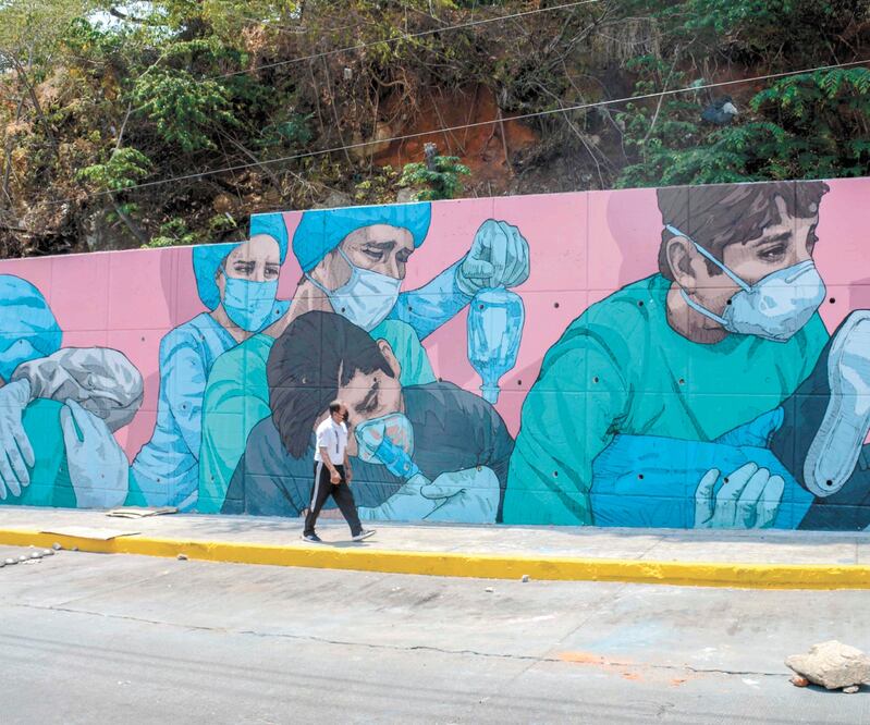 Una mujer camina junto a un mural alusivo al Covid-19 en Acapulco, Guerrero, estado que representa un desafío de seguridad para la 4T, dice el ICG. FRANCISCO ROBLES. AFP