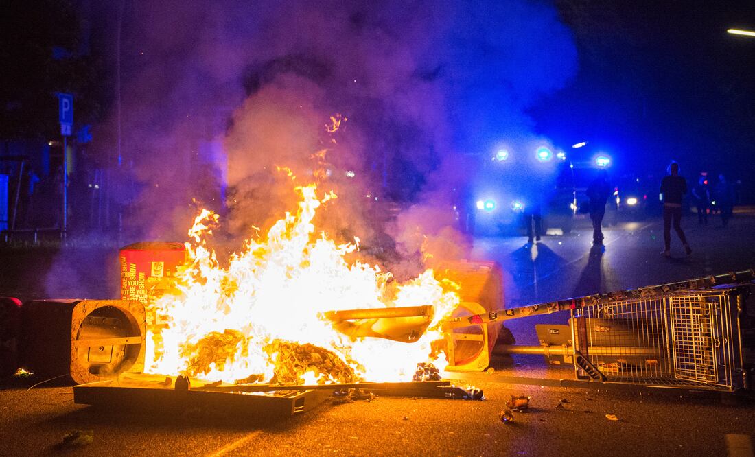 Policías tras una barricada en llamas en la llamda zona de "Schanzenviertel", durante la cumbre del G20 en Hamburgo, en la madrugada. (AP)