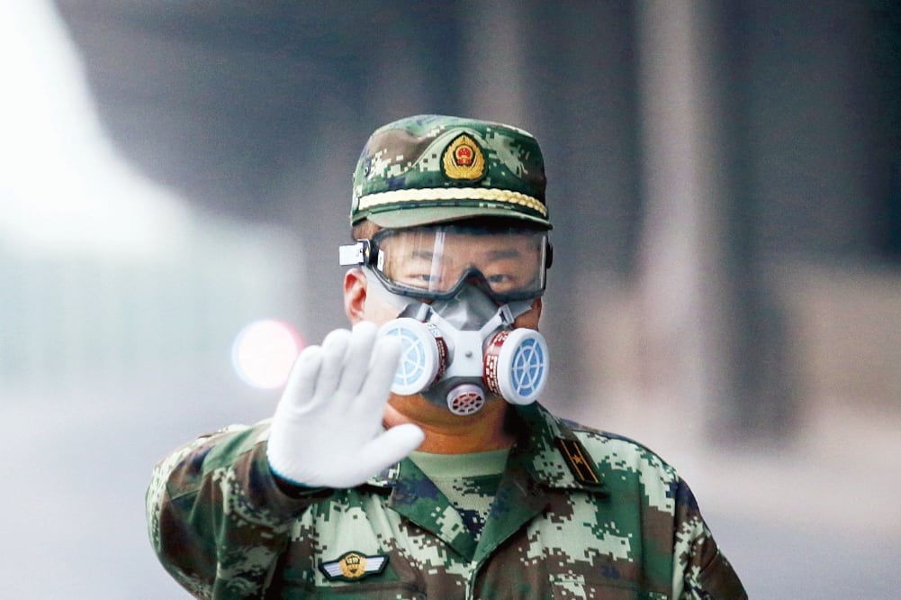 Vigilancia.Un oficial, con un cubrebocas, impide el paso hacia la zona residencial afectada por las explosiones en Tianjín (Especial)