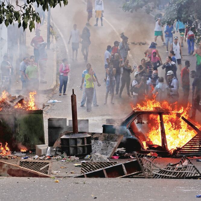 Manifestantes detrás de una barricada en llamas, durante una protesta cerca de un puesto de la Guardia Nacional en Caracas, Venezuela. CARLOS GARCÍA RAWLINS. REUTERS