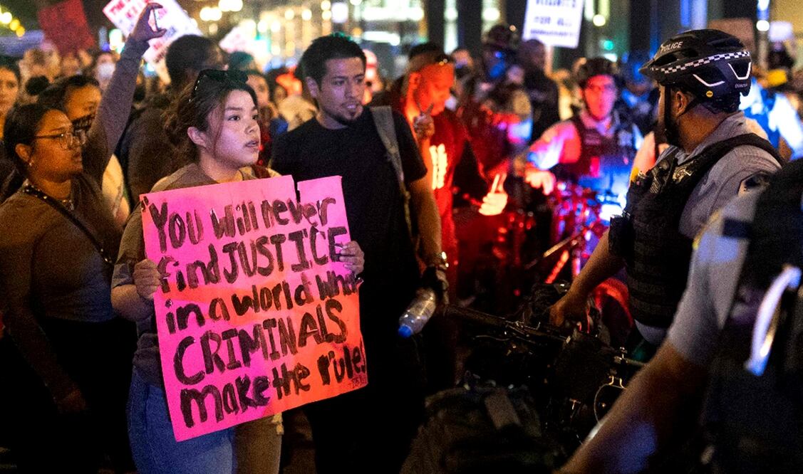 Una manifestante sostiene un cartel con con la leyenda "Nunca encontrarás justicia en un mundo donde los criminales hacen las reglas" durante una protesta contra las redadas migrantes en Chicago, Illinois, el 10 de junio de 2025. Foto: AFP