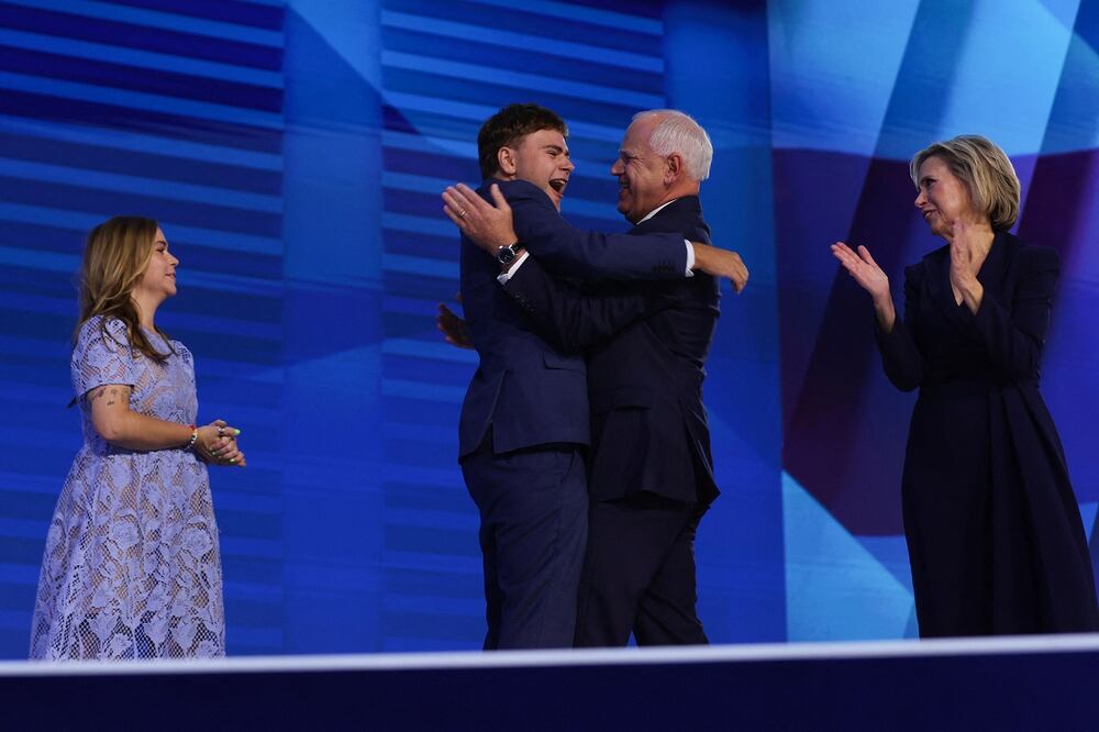 Gus abraza a su padre, el candidato vicepresidencial demócrata Tim Walz, al término de su discurso de aceptación. FOTO: AFP