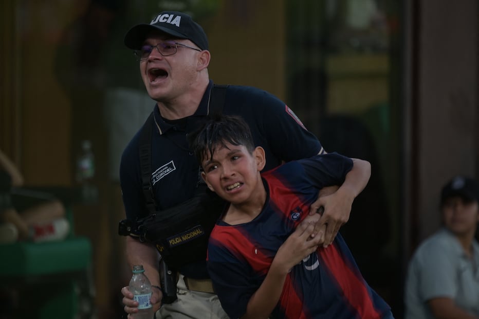Policía ayuda a fan en medio de la pelea en las gradas del Olimpia vs Cerro Porteño / Foto: AFP