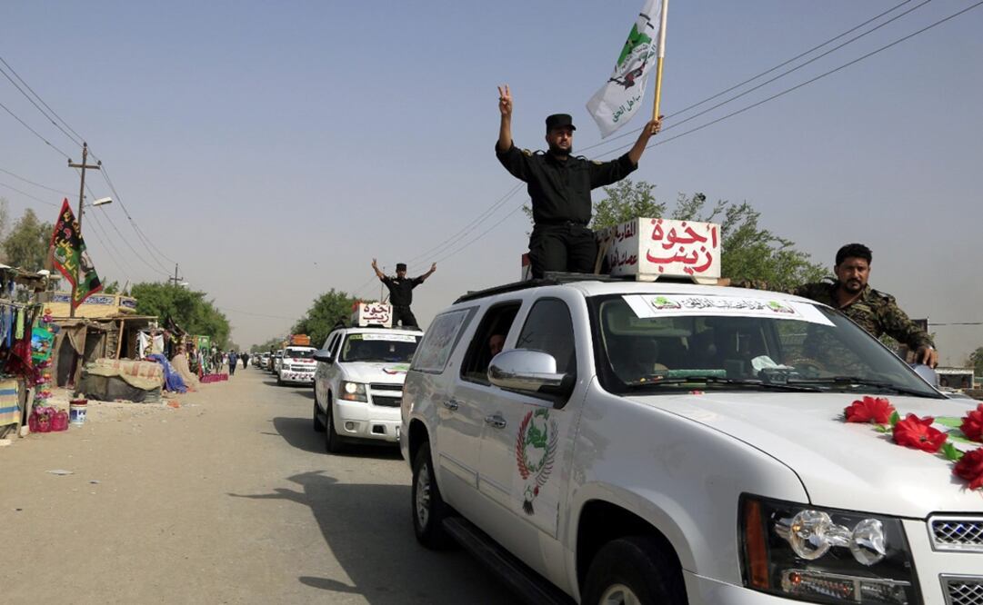 Miembros de la milicia chiíta iraquí, Asaib Ahl Al-Haq, muestran el signo de la victoria, mientras transportan los féretros de sus compañeros muertos en la ciudad de Baiji en enfrentamientos con el Estado Islámico (Foto: EFE)
