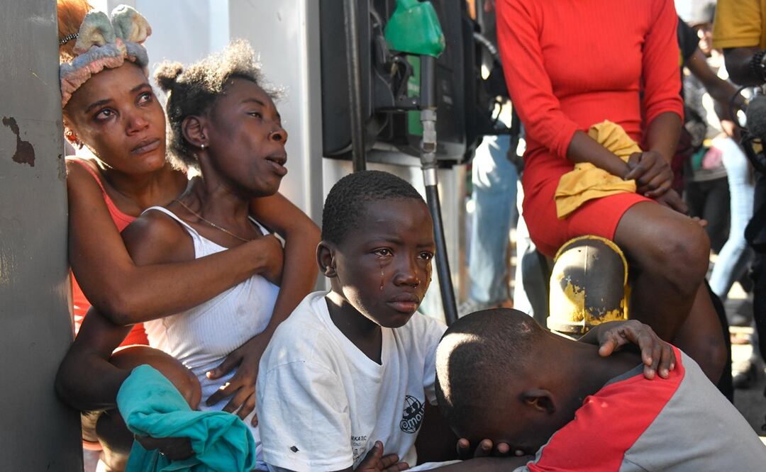 Dos mujeres y dos niños reaccionan luego de ver el cadáver de un familiar en la calle este lunes, en Puerto Príncipe (Haití). Foto. EFE