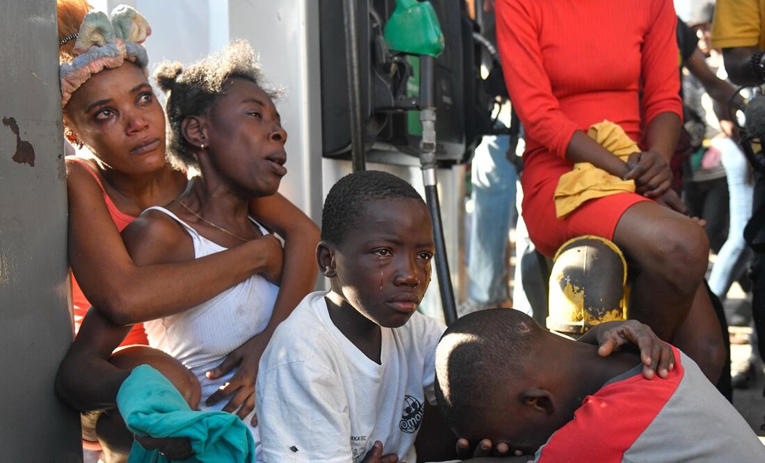 Dos mujeres y dos niños reaccionan luego de ver el cadáver de un familiar en la calle este lunes, en Puerto Príncipe (Haití). Foto. EFE