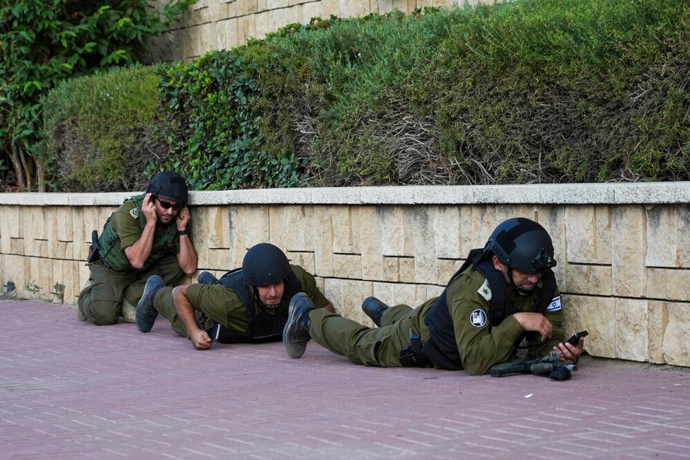 Los soldados israelíes se cubren mientras suena una sirena que advierte de la llegada de cohetes disparados desde la Franja de Gaza, en Ashkelon. Foto: AP
