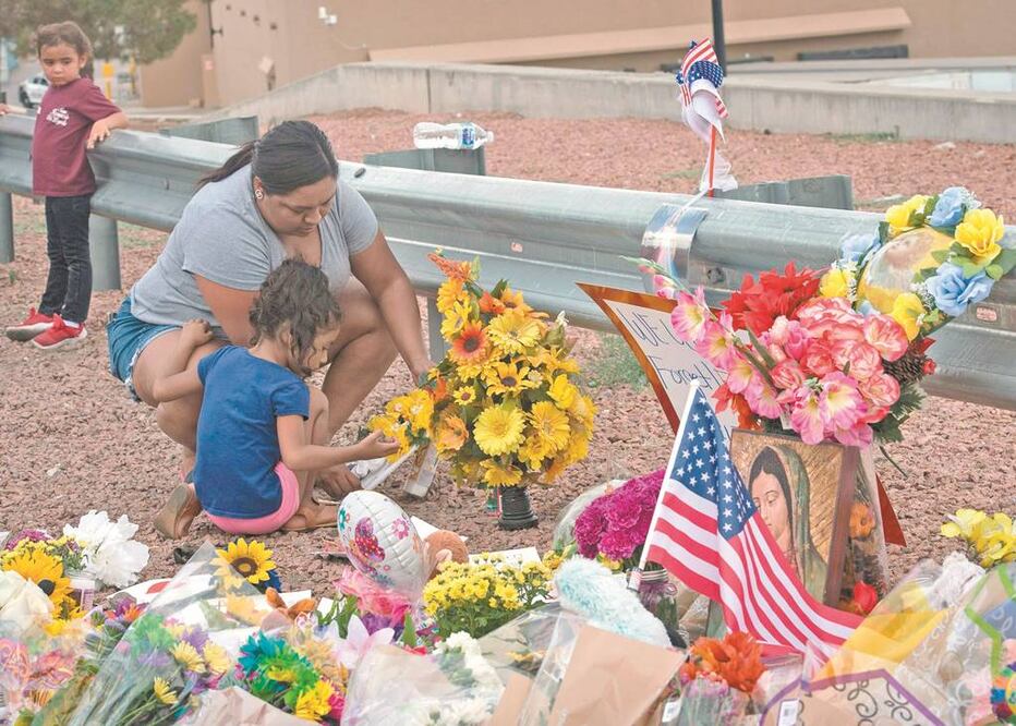 Una familia enciende una vela en un memorial frente al Walmart, donde un tiroteo dejó 20 personas muertas el sábado pasado en El Paso, Texas. Foto/MARK RALSTON. AFP