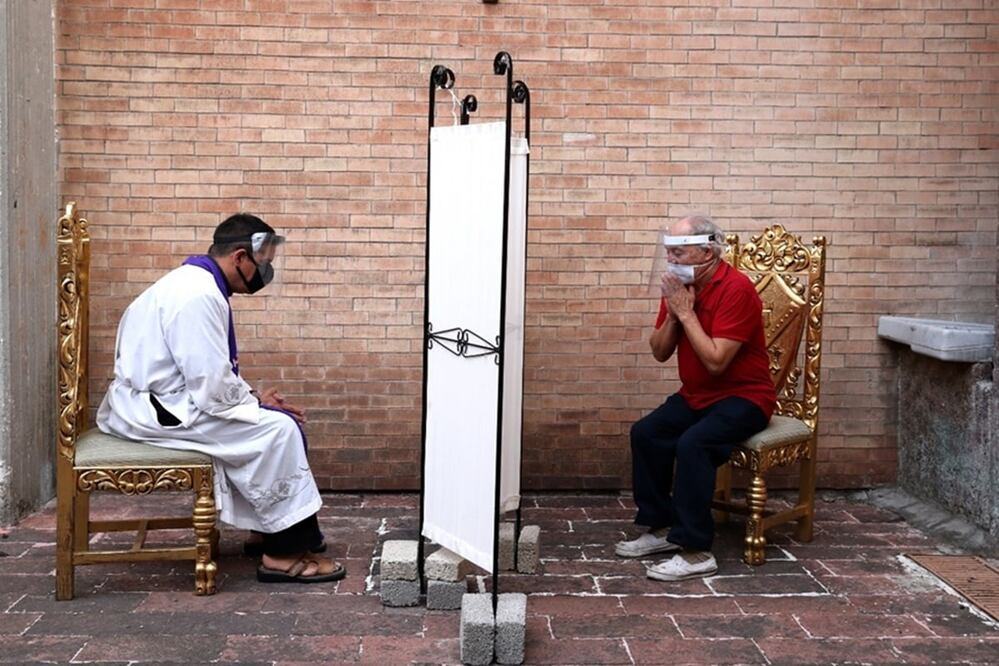 Con una mampara de por medio y en un espacio abierto el sacerdote escucha la confesion de uno de los feligreses. Fotos: Valente Rosas. El Universal