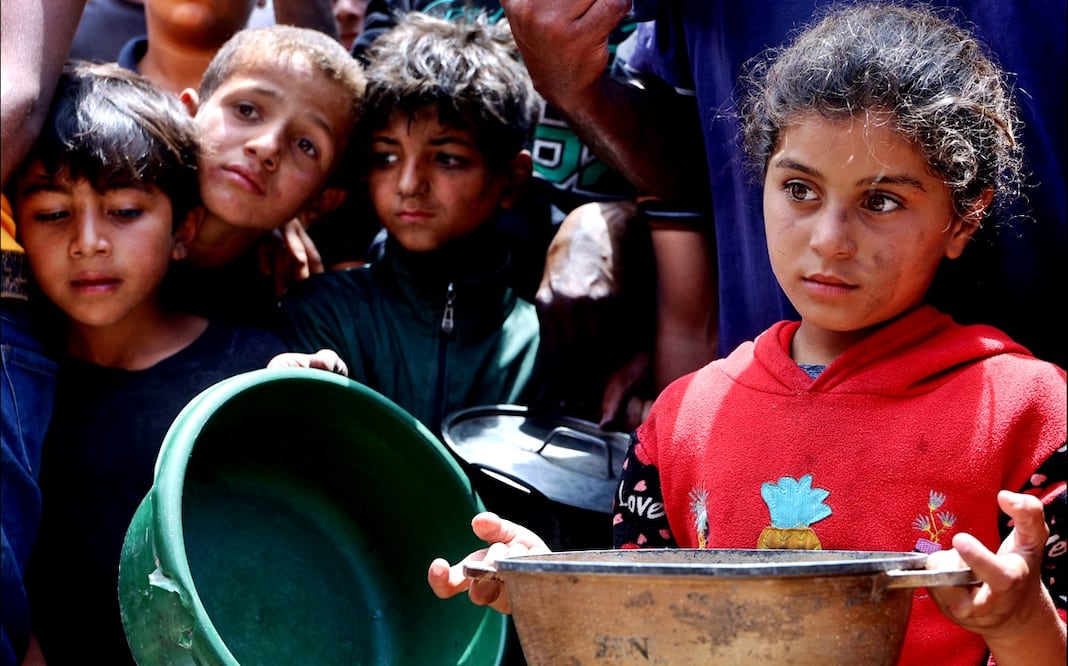 Niños esperan ansiosos la repartición de comida frente a un camión de distribución cerca del puerto de la ciudad de Gaza, el 22 de mayo de 2025. Foto: AFP