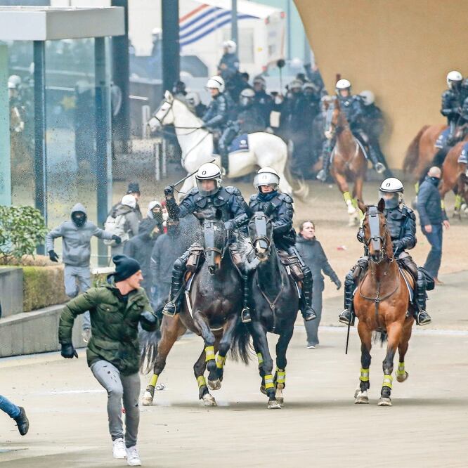 Elementos de la Policía Montada persiguen a manifestantes de extrema derecha que protestaban ayer contra el pacto migratorio de la ONU. (JULIEN WARNAND. EFE)
