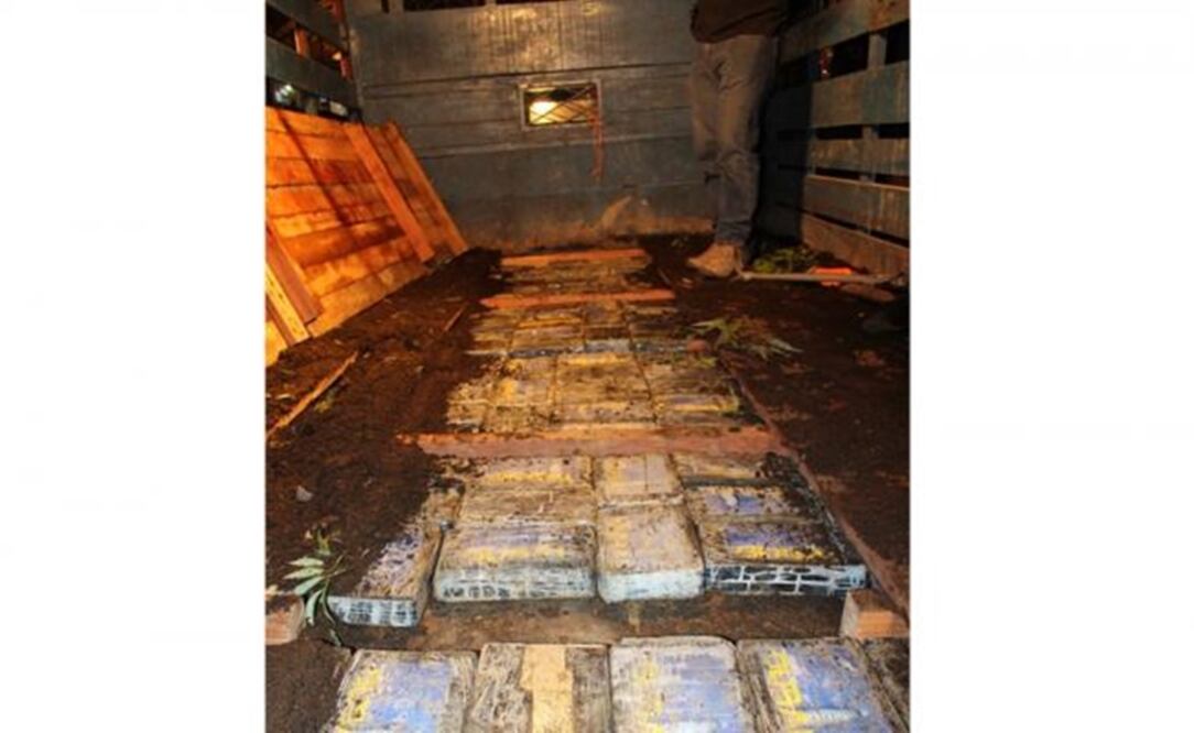 Un agente costarricense permanece al lado de unos 237 kilos de cocaína dentro de paquetes cubiertos por tierra, decomisados a la red de narcotráfico desarticulada anoche en Costa Rica. (Foto: Organismo de Investigación Judicial)