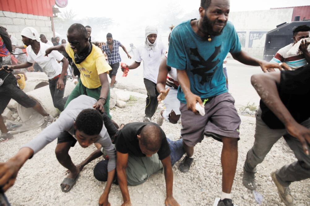 Manifestantes haitianos huyen de la policía en Puerto Príncipe. Foto: ANDRES MARTINEZ CASARES. REUTERS