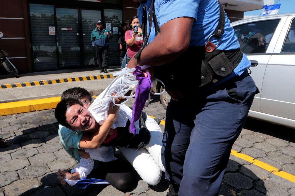 Un policía de Nicaragua arrastra el domingo en Managua a una opositora nicaragüense para detenerla, mientras otra intenta impedirlo, como parte de una oleada de arrestos ordenada por el presidente de ese país, Daniel Ortega (Foto: Reuters)