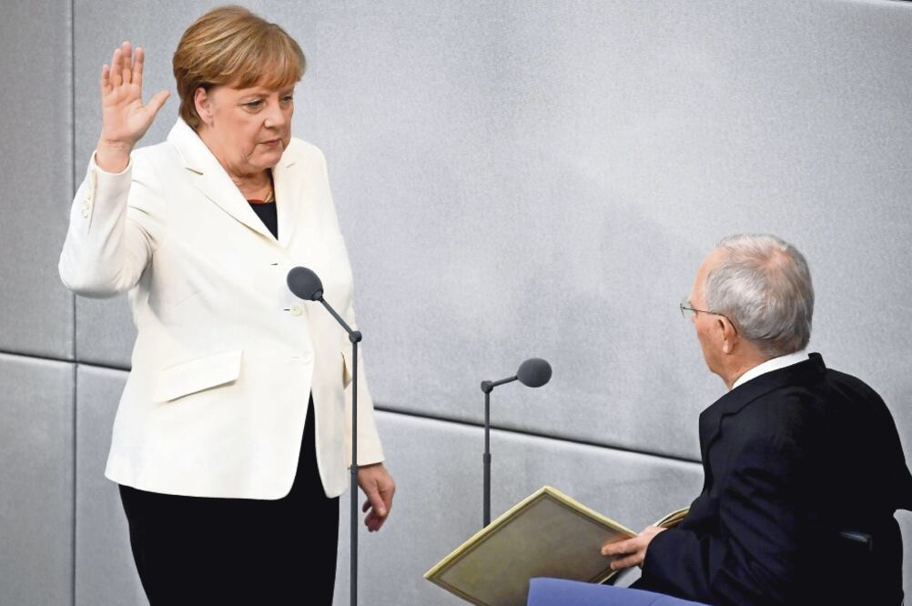 La canciller alemana, Angela Merkel, juró ayer su cargo ante el presidente del Parlamento alemán (Bundestag), Wolfgang Schaeuble (der.). Este será su cuarto mandato al frente del gobierno (CLEMENS BILAN. EFE)