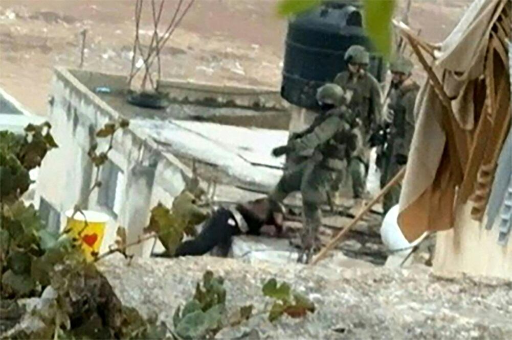 Una imagen tomada de un vídeo de AFPTV muestra a un soldado israelí pateando el cuerpo de un palestino en el techo de un edificio en Qabatiyah, al sur de Jenin, en la ocupada Cisjordania, durante una incursión militar el 19 de septiembre de 2024. Foto: AFP