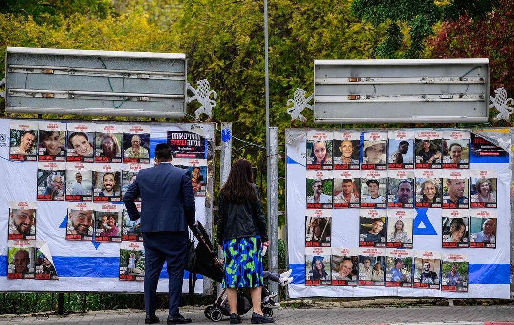Una pareja con niños mira retratos de rehenes israelíes retenidos en Gaza desde el ataque del 7 de octubre por militantes de Hamas. Foto: AFP