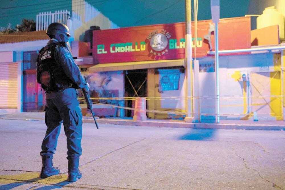 Un agente custodia las instalaciones del bar El Caballo Blanco, donde murieron al menos 28 personas. Foto: ÁNGEL HERNÁNDEZ. EFE