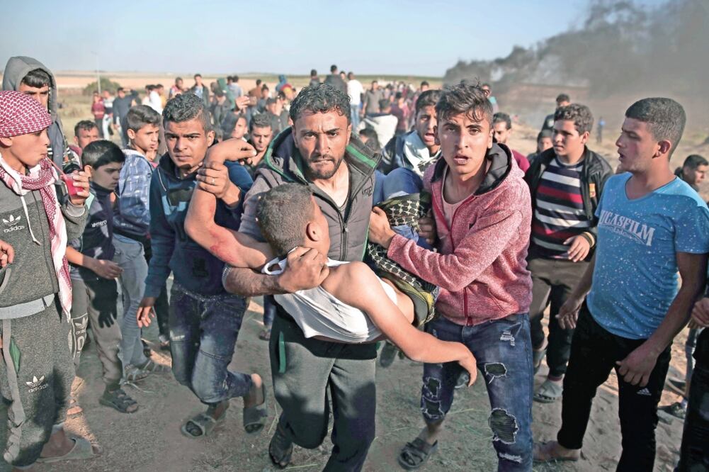 Manifestantes palestinos cargan a un compañero herido por disparos de las tropas israelíes, ayer, en la Franja de Gaza. (KHALIL HAMRA. AP)