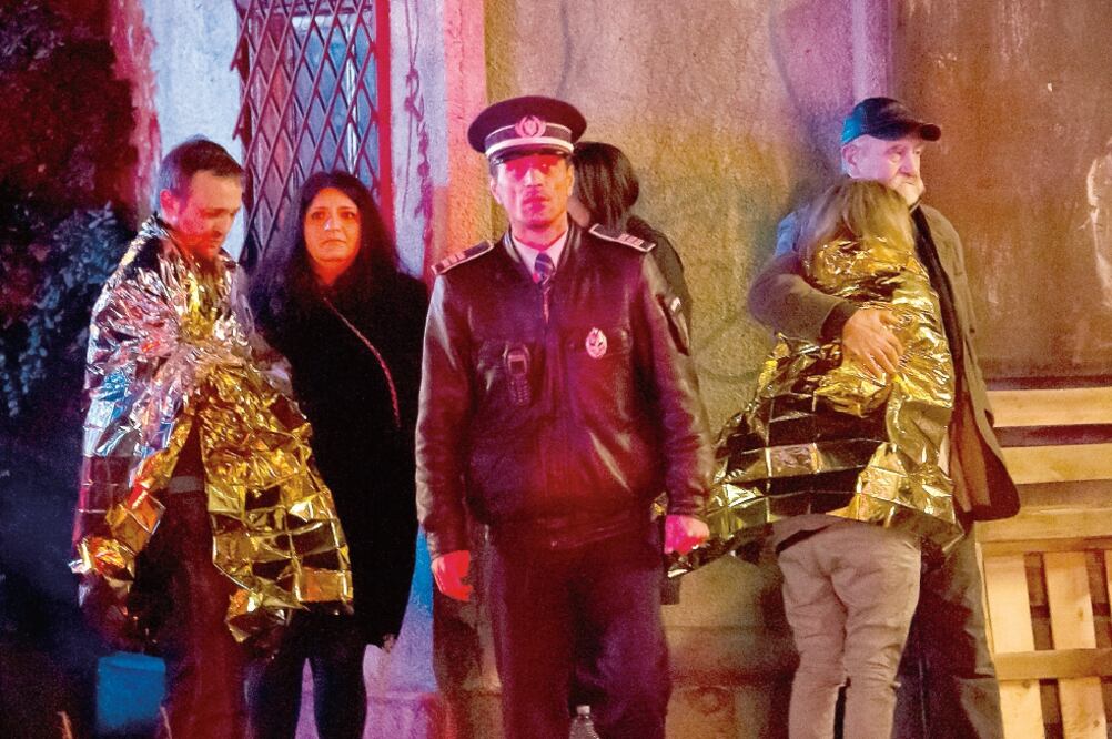 Sobrevivientes del incendio en una discoteca en Bucarest, anoche, son cubiertos con mantas térmicas, mientras las autoridades revisan el lugar. (VADIM GHIRDA. AP)