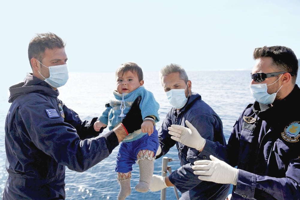 Rescatistas de la Guardia Costera de Grecia cargan a un bebé, durante una operación de rescate ayer en conjunto con las autoridades de Turquía (GIORGOS MOUTAFIS. REUTERS)