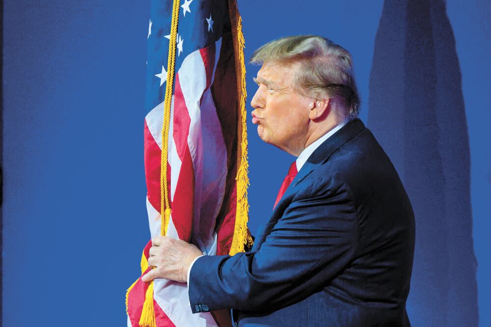 Donald Trump besa la bandera de EU en la CPAC 2024. Foto: Mndel Ngan / AFP