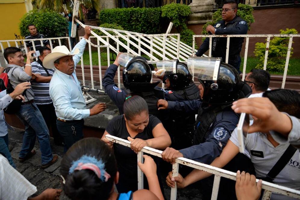 Integrantes de la Coordinadora Morelense de Movimientos Ciudadanos superaron la barricada metálica que instaló la Policía Antimotín para impedir el paso de manifestantes hasta el Congreso de Morelos. 