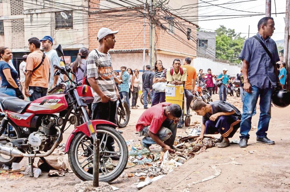 Dos hombre buscaban ayer entre los escombros, afuera de varios comercios que fueron saqueados principalmente en el populoso barrio de El Valle, al oeste de la ciudad de Caracas, Venezuela. (MIGUEL GUTIÉRREZ. EFE)