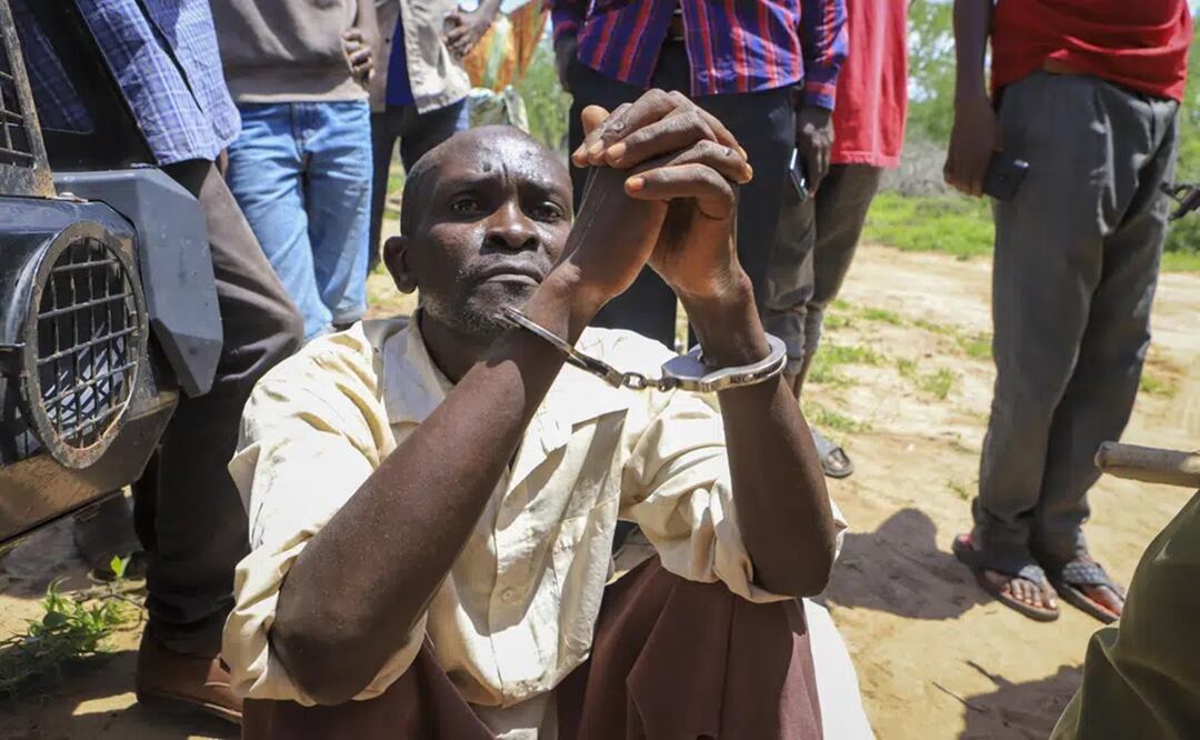 Un hombre no identificado está sentado esposado después de ser arrestado acusado de tener relación con el pastor Paul Mackenzie, en un bosque cerca de la aldea Shakahola. Foto: AP