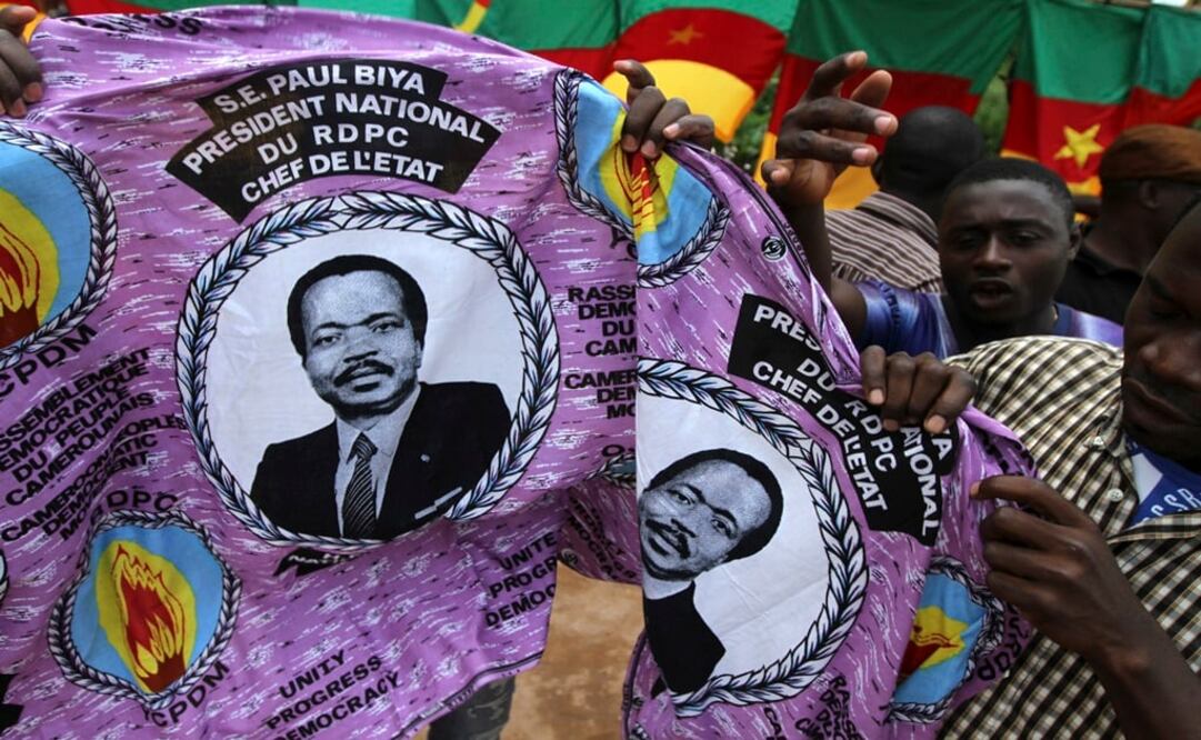 People hold a piece of cloth with pictures of Cameroon's President Paul Biya, near a street stall at the Carrefour Wada district in the capital Yaounde - Photo: Akintunde Akinleye/REUTERS