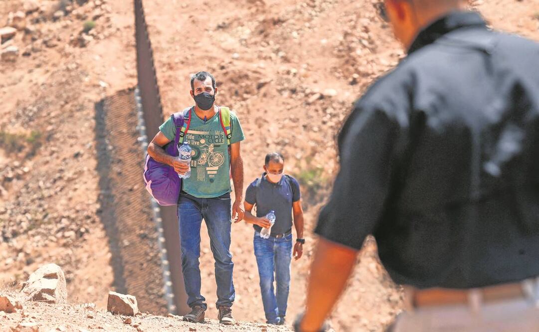 Un agente fronterizo detiene a inmigrantes brasileños que cruzaron la frontera en Otay Mesa, California, en agosto de 2021. Foto: Archivo AFP