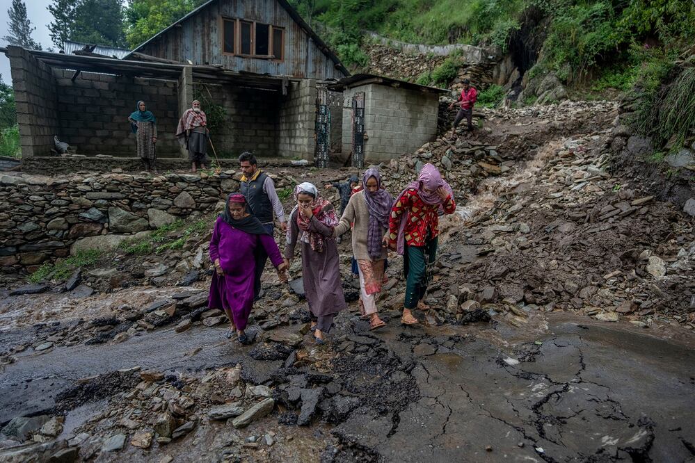 Los aldeanos de Cachemira caminan por una carretera dañada por las inundaciones repentinas después de un aguacero en las afueras de Srinagar, Cachemira controlada por India. Foto: AP