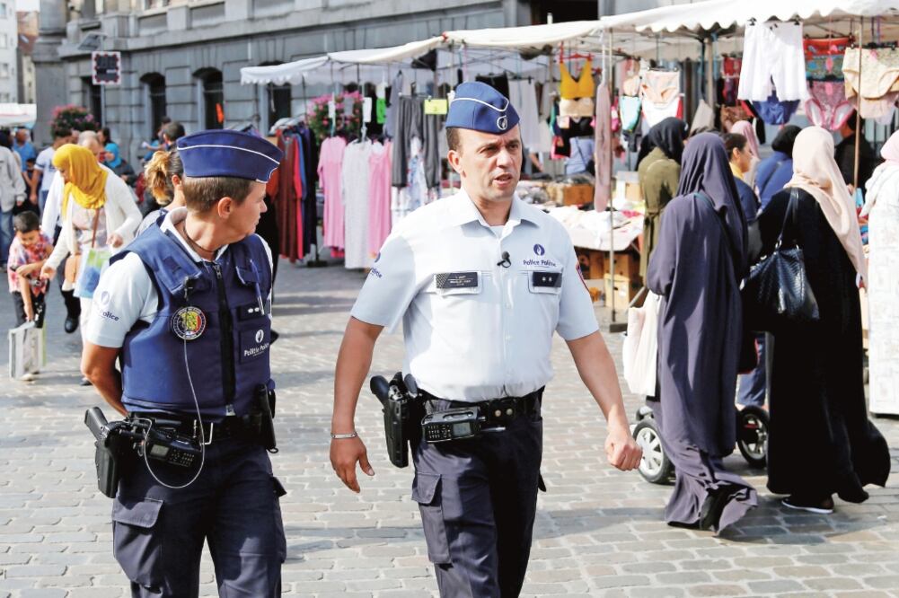 Oficiales belgas patrullan un mercado en el distrito Molenbeek de Bruselas. En este barrio la gente se ha involucrado en la lucha contra el radicalismo (FRANCOIS LENOIR. REUTERS)