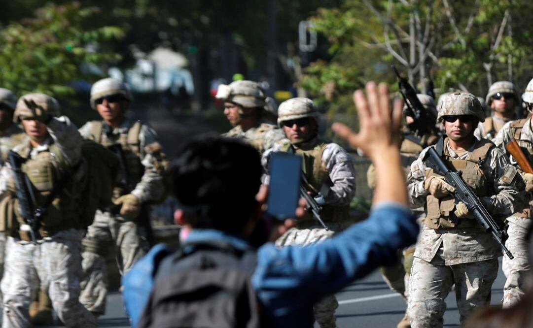 A demonstrator gestures as Chilean soldiers advance carrying their weapons, during a protest against Chile's state economic model in Santiago, Chile - Photo: Edgard Garrido/REUTERS