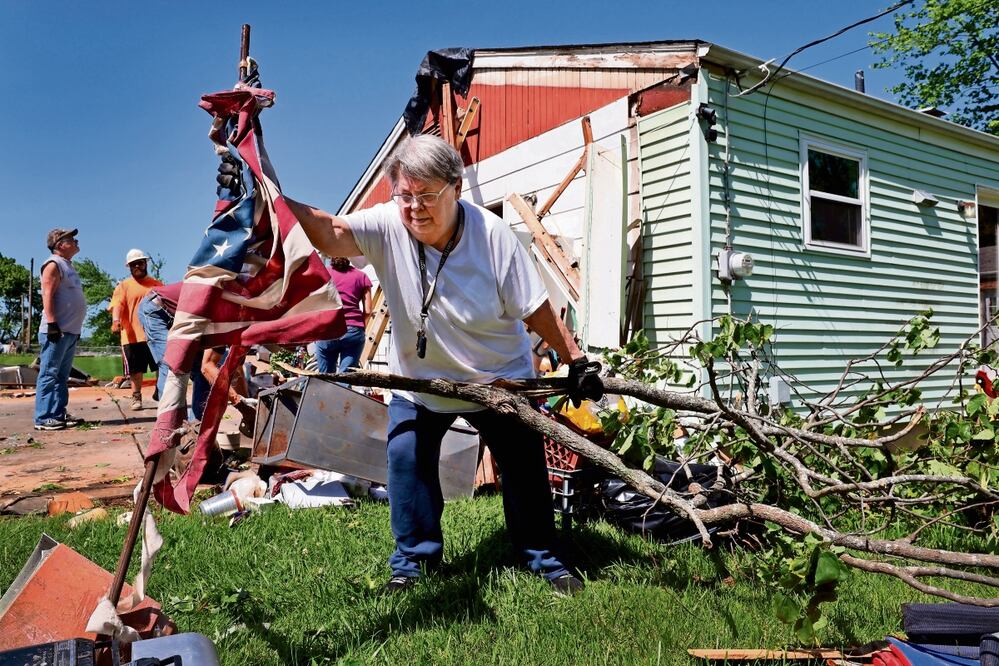 Patti Manley quita una bandera estadounidense que quedó hecha trizas, luego de una violenta tormenta que impactó Mehlville, en Missouri. Foto: AP