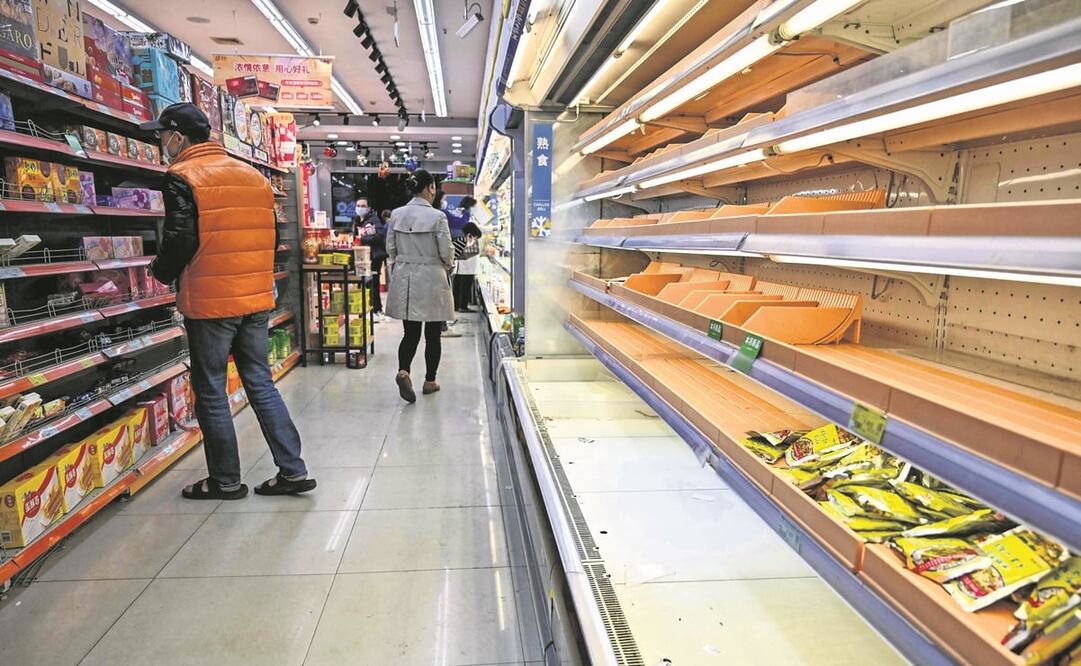 Compradores buscan en los supermercados, que se han quedado con los estantes vacíos durante el confinamiento por etapas en Shanghái. Foto: Héctor Retamal. AFP