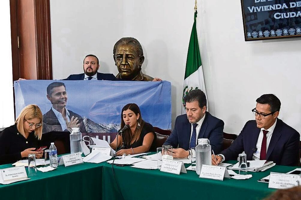 El panista Ricardo Rubio mostró una manta con la imagen del secretario Carlos Ulloa, al criticarlo por supuestos actos anticipados de campaña. Foto: Especial