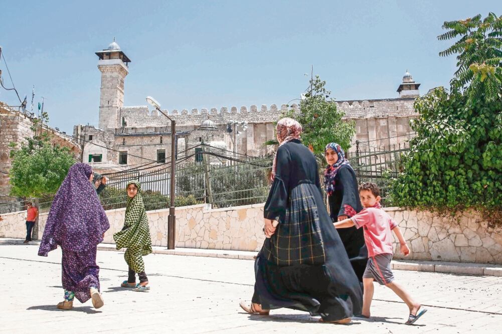 Personas caminan afuera de la Tumba de los Patriarcas (para los judíos) conocida también como la Mezquita Al Ibrahim (para los musulmanes), en Hebrón. (HAZEM BADER. AFP)