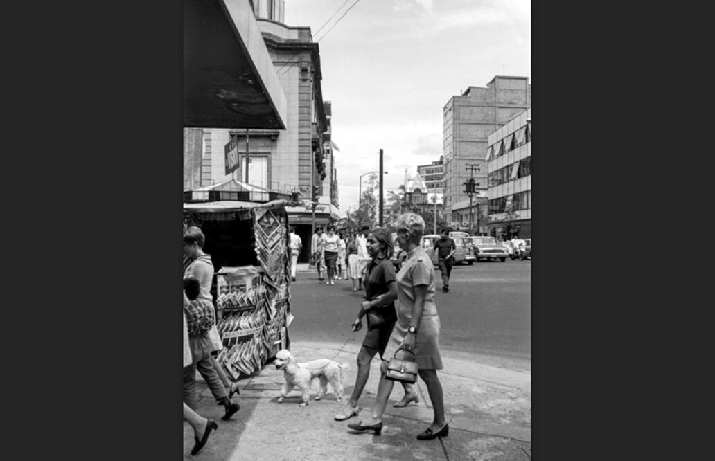 Dos mujeres pasean a un french poodle junto a un quiosco de revistas situado en la esquina de Niza y Hamburgo, en el corazón de la Zona Rosa, en septiembre de 1968. Al fondo del lado derecho se encuentra la residencia porfiriana que permanece hasta hoy en la esquina de la Hamburgo e Insurgentes. Imagen cortesía: Bob Schalkwijk