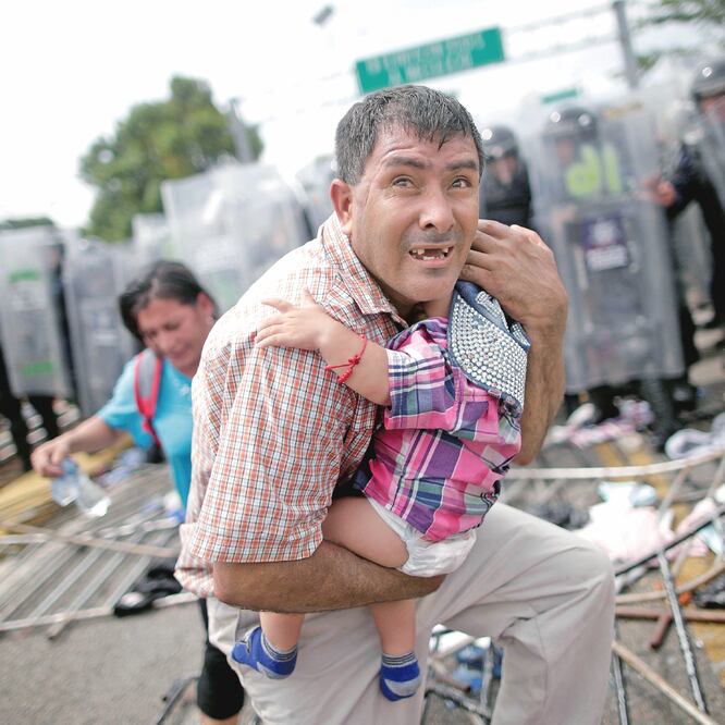 Un migrante hondureño protege a su hijo después de que sus compañeros de la caravana irrumpieron en un puesto fronterizo en Guatemala, en Ciudad Hidalgo, México. Foto: UESLEI MARCELINO. REUTERS