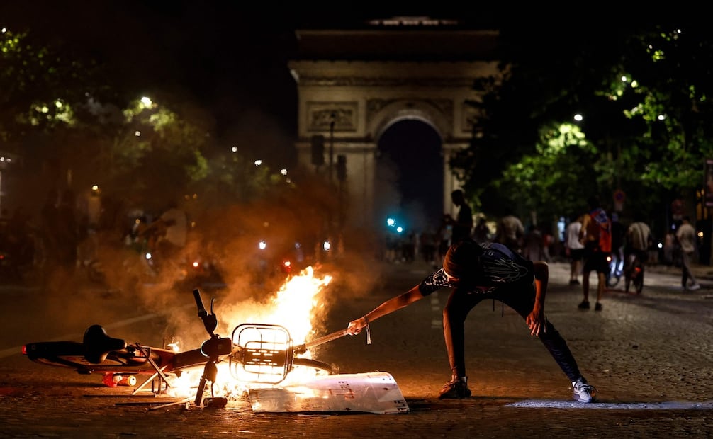 Un ciudadano manipula un objeto cerca de una bicicleta en llamas durante las celebraciones del PSG en París tras la final de la Liga de Campeones (30/05/2026). Foto: AFP