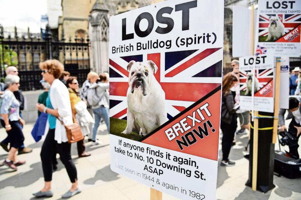 Británicos pasan cerca de pancartas a favor de la salida de Reino Unido de la Unión Europea, en Londres. Foto: TOBY MELVILLE. REUTERS