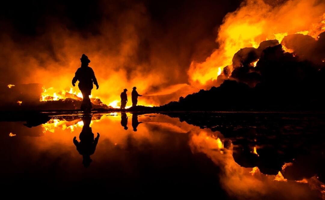 The picture hows a group of firefighters trying to extinguish a fire at a recycling plant in Mexicali, Baja California - Photo: Víctor Medina/2019 Sony World Photography Awards