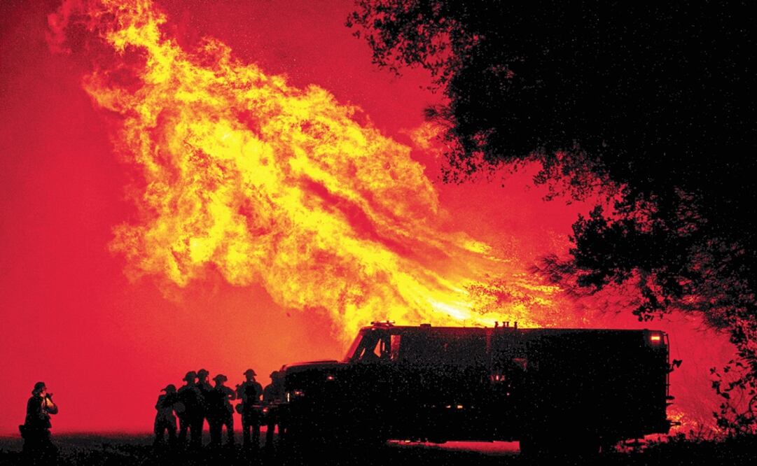 Butte county firefighters watch as flames tower over their truck during the Bear fire in Oroville, California - Photo: Josh Edelson/AFP