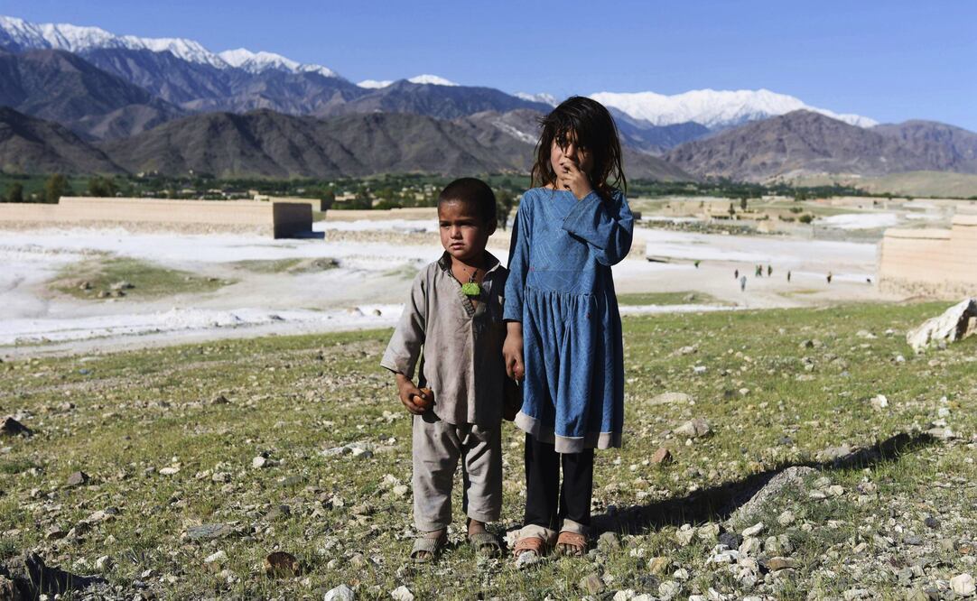 Dos niños afganos posan delante de la zona montañosa sobre la que EE.UU. lanzó ayer la mayor bomba no-nuclear, la llamada "Madre de todas las bombas" (Foto: EFE)