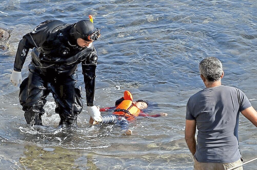 Un buzo de un guardacostas griego rescata el cuerpo de un niño que murió ahogado al naufragar una embarcación con refugiados cerca de la isla de Lesbos (GIORGOS MOUTAFIS. REUTERS)