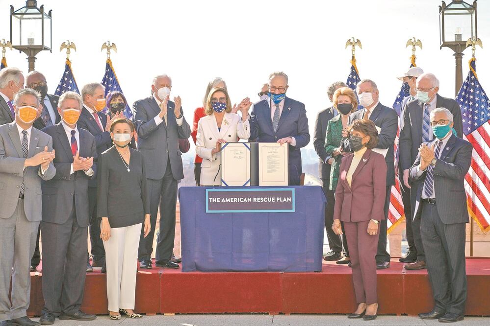 La presidenta demócrata de la Cámara Baja, Nancy Pelosi (centro), con senadores y congresistas tras aprobar el paquete de rescate. Foto: Drew Angerer/ AFP