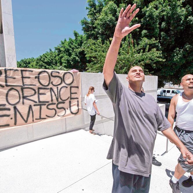 Familiares afuera de un centro de detención en Los Ángeles, California, saludan a uno de los suyos detenido ayer en una redada del ICE. MARK RALSTON. AFP