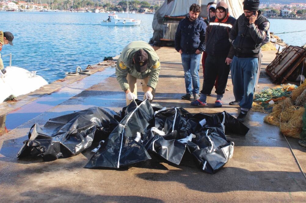 Personas revisan los cadáveres de migrantes que se ahogaron ayer cuando intentaban alcanzar Grecia, en un puerto cerca de Izmir, Turquía. Fueron dos las embarcaciones que se hundieron frente a dos islas griegas (AP)